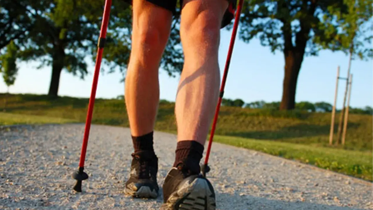 Nogi w butach do nordic walking, z kijkami w rękach, na ścieżce. Dowiedz się, jak prawidłowo założyć buciki na kijki nordic walking.