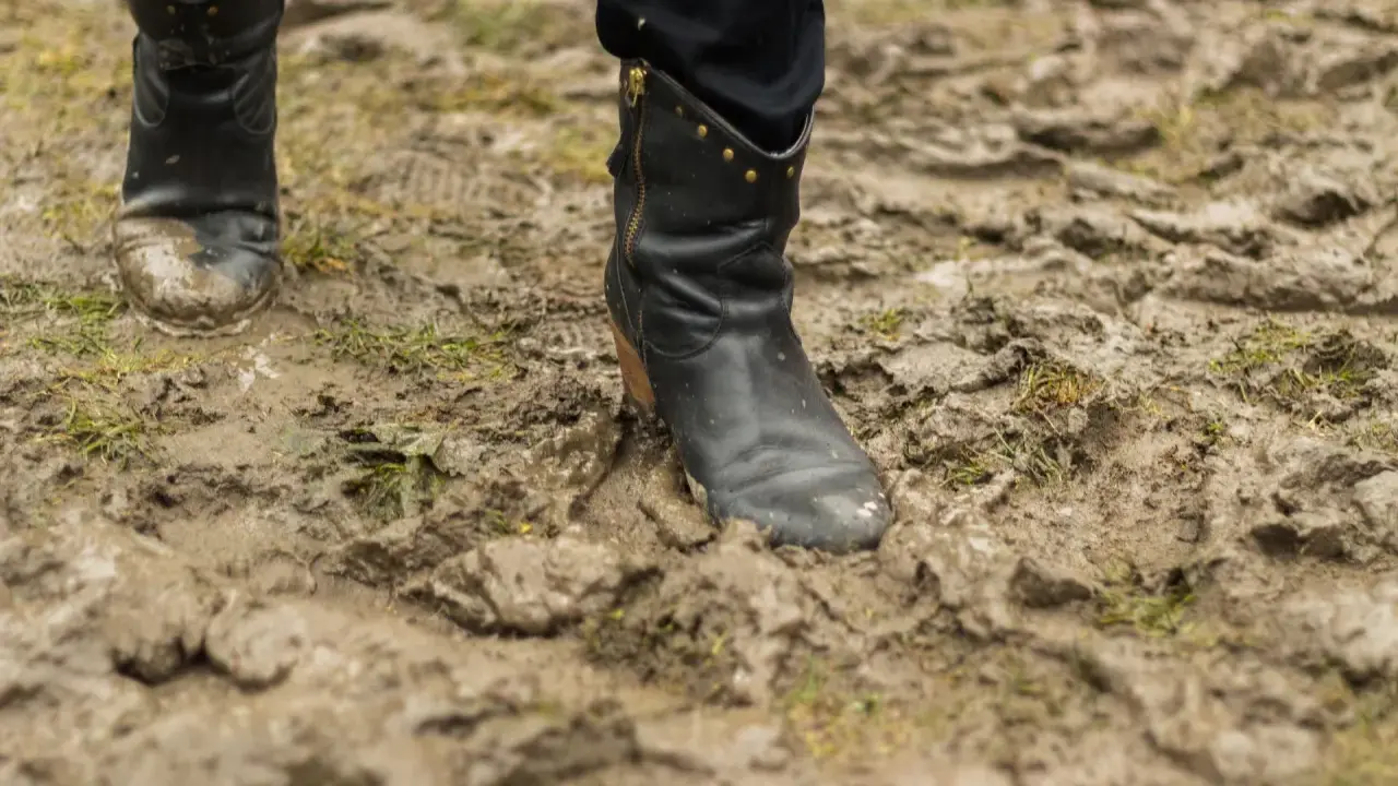Czarne buty w błocie, po spacerze po deszczu. Czas dowiedzieć się, jak wyczyścić buty z błota, by znów lśniły.