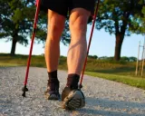 Nogi w butach do nordic walking, z kijkami w rękach, na ścieżce. Dowiedz się, jak prawidłowo założyć buciki na kijki nordic walking.