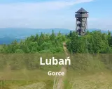 Wieża widokowa na górze Lubań w Gorcach, otoczona zielonymi lasami i pagórkami.