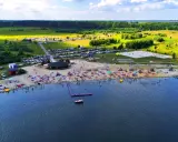Tłoczna plaża nad jeziorem na Dolnym Śląsku, z ludźmi opalającymi się, pływającymi i bawiącymi się.