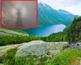 Widok na górskie jezioro z mglistym zjawiskiem, gdzie widać cień postaci otoczony tęczową aureolą - to efekt brockenu.