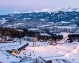 Ośnieżone stoki i kolejka na Kasprowy Wierch to jedne z wielu zakopiańskich atrakcji. W tle widać panoramę miasta i Tatry.
