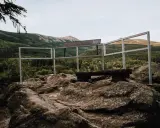 Kamienna platforma widokowa na szczycie, z ławką i balustradą, oferuje panoramę gór porośniętych lasem. To idealne miejsce na odpoczynek i podziwianie krajobrazu, niczym z legend o kruczych skałach.