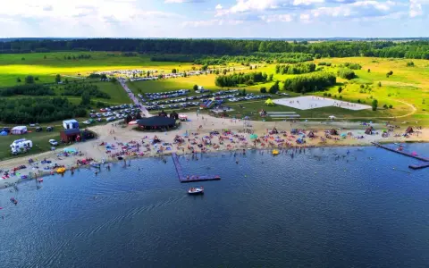 Tłoczna plaża nad jeziorem na Dolnym Śląsku, z ludźmi opalającymi się, pływającymi i bawiącymi się.