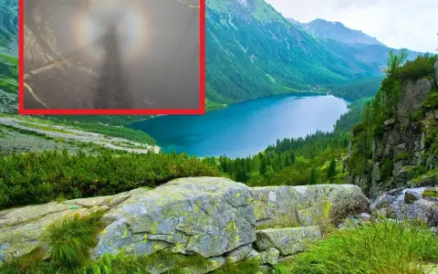 Widok na górskie jezioro z mglistym zjawiskiem, gdzie widać cień postaci otoczony tęczową aureolą - to efekt brockenu.