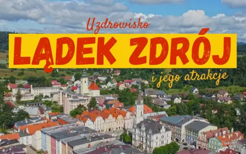 Widok na Lądek Zdrój i jego atrakcje. Miasto z kolorowymi kamienicami, kościołem i zielonymi wzgórzami w tle.