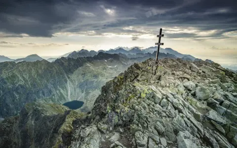 Kamienisty szczyt z krzyżem, widok na Tatry i jezioro. Krywań szlak w chmurach.