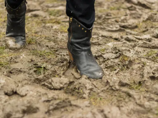 Czarne buty w błocie, po spacerze po deszczu. Czas dowiedzieć się, jak wyczyścić buty z błota, by znów lśniły.