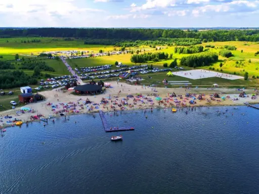 Tłoczna plaża nad jeziorem na Dolnym Śląsku, z ludźmi opalającymi się, pływającymi i bawiącymi się.