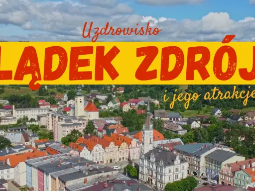 Widok na Lądek Zdrój i jego atrakcje. Miasto z kolorowymi kamienicami, kościołem i zielonymi wzgórzami w tle.