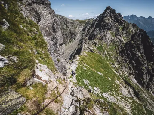 Wąska ścieżka z łańcuchami na skraju orlej perci, prowadząca przez skaliste zbocza Tatr.