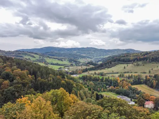 Jesienny krajobraz Gór Sowich z kolorowymi drzewami i pagórkami.