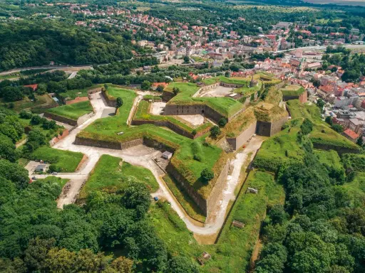 Imponująca twierdza w Kłodzku, jedna z największych atrakcji regionu, rozciąga się na wzgórzu, otoczona zielenią i miastem.