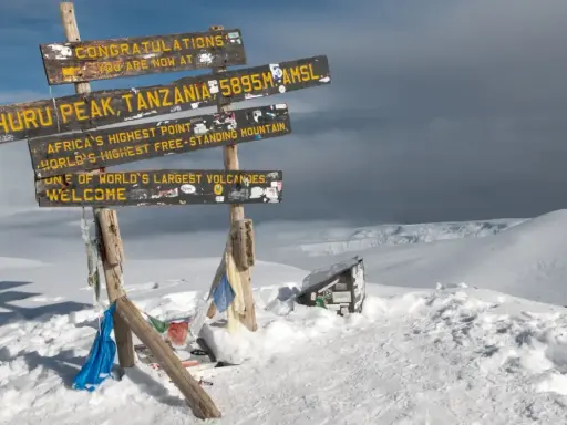 Snieg w Afryce na szczycie Uhuru Peak, Tanzania. Znaki informują o wysokości 5895 m n.p.m. i o tym, że to najwyższy punkt Afryki.