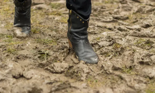 Czarne buty w błocie, po spacerze po deszczu. Czas dowiedzieć się, jak wyczyścić buty z błota, by znów lśniły.