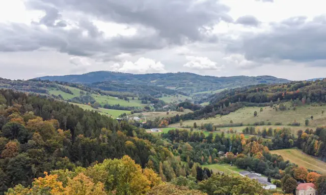 Jesienny krajobraz Gór Sowich z kolorowymi drzewami i pagórkami.