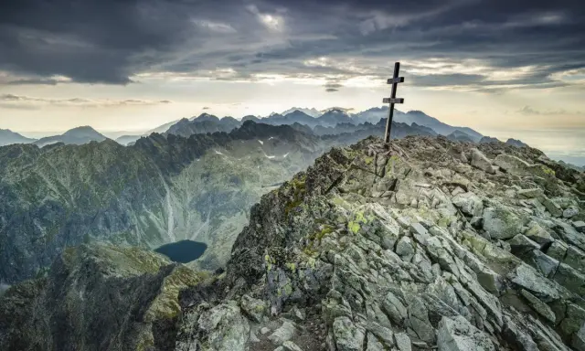 Kamienisty szczyt z krzyżem, widok na Tatry i jezioro. Krywań szlak w chmurach.