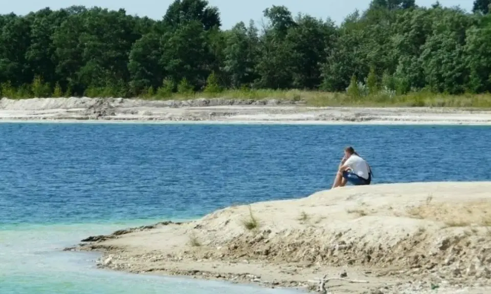 Samotny mężczyzna siedzi na brzegu, kontemplując turkusową wodę. To spokojne miejsce, jakby zapomniany osadnik gajówka.