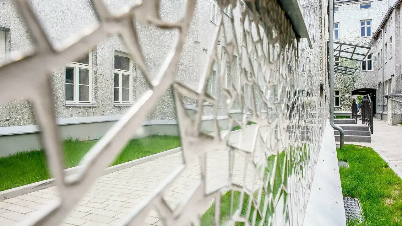 Co ciekawego w Łodzi? Fasada budynku pokryta mozaiką z luster, odbijająca zieleń i architekturę.
