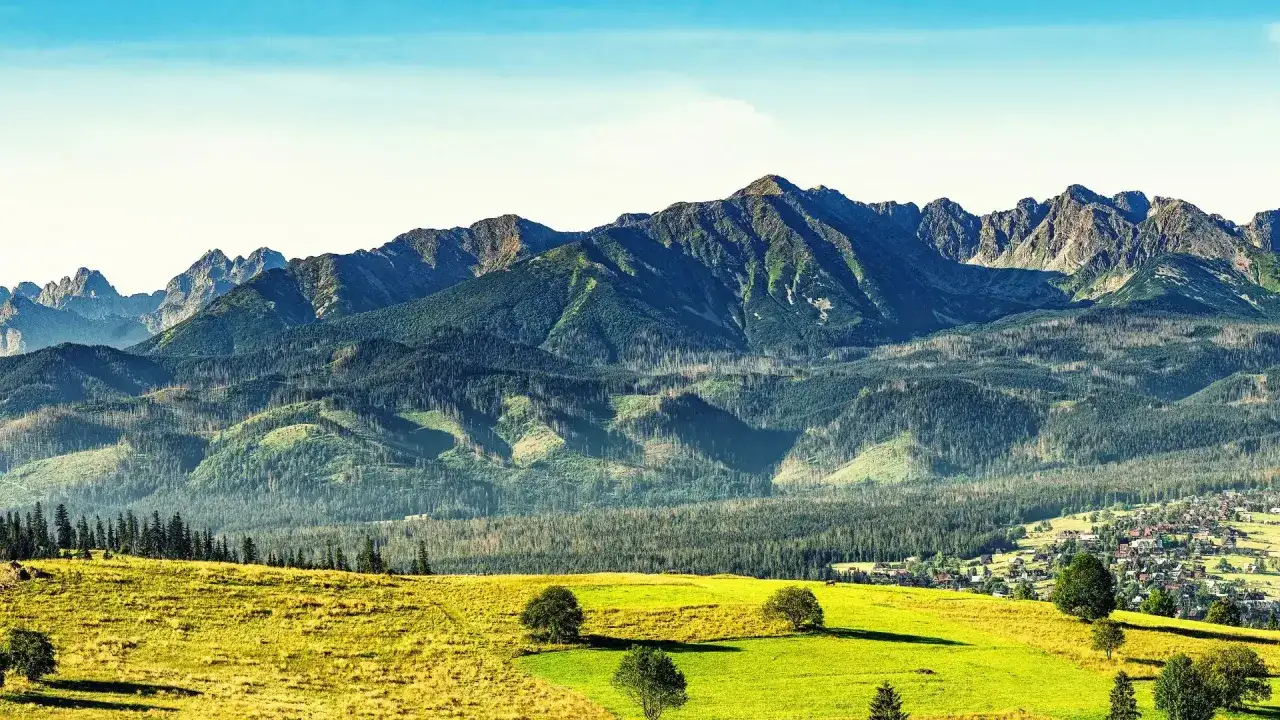Widok na Tatry z zielonymi łąkami i lasami. Idealne miejsce na pierwsze g&oacute;rskie wędr&oacute;wki, czyli tatry dla początkujących.