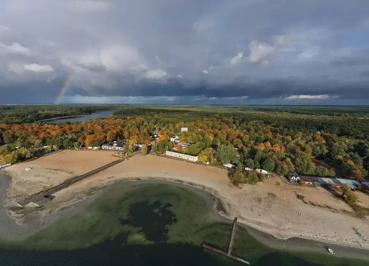 Jesień nad najładniejszymi jeziorami w Wielkopolsce. Tęczowy łuk nad lasem i piaszczysta plaża.