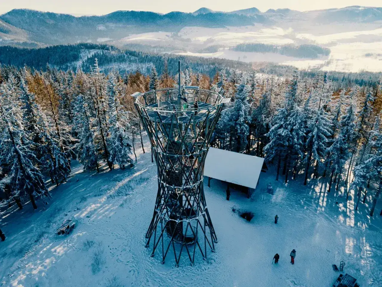 Wieża widokowa na górze borowej w zimowej scenerii. Śnieg pokrywa drzewa i ziemię, tworząc bajkowy krajobraz.