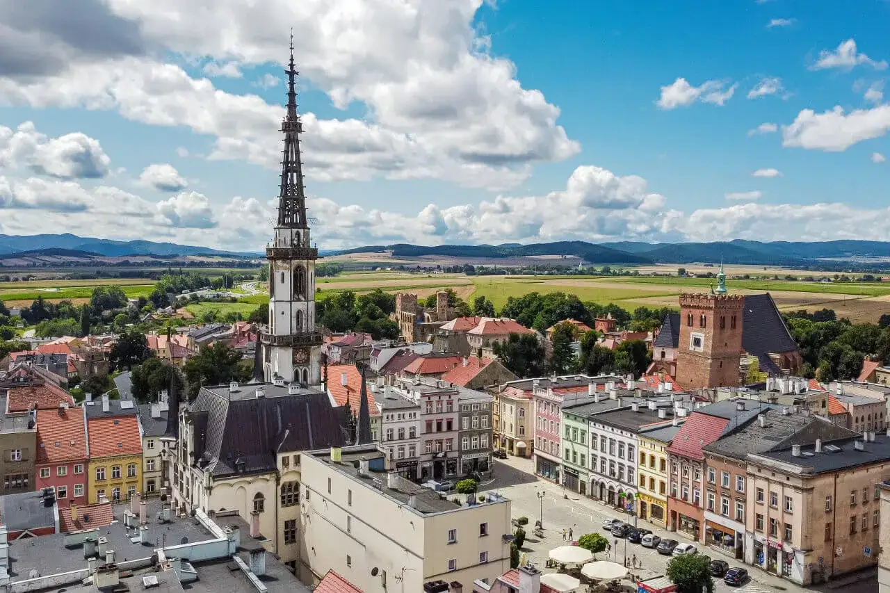 Widok na rynek i wieżę ratuszową w Ząbkowicach Śląskich. Kolorowe kamienice i ruiny zamku tworzą urokliwe ząbkowice śląskie atrakcje.